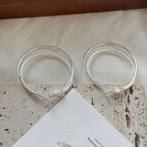 Detail of silver double layered hoop earrings with polished and frosted metal textures
