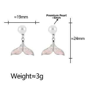 Close-up of pearl earrings with fishtail pendants filled with pink and white crystals