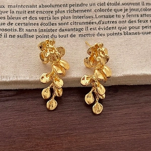 Dettaglio orecchini vintage a foglia d'oro con design floreale e lunghe nappe pendenti