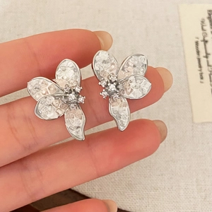 Elegant floral stud earrings with crushed stones and rhinestones held by hand