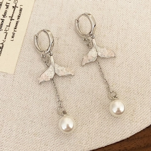 Elegant silver fishtail earrings with pink crystals and pearls on white linen