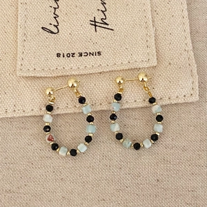 Handmade teardrop earrings with black beads and blue stones on rustic linen background