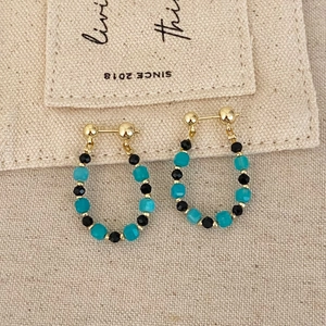 Handcrafted teardrop bead earrings featuring blue and black faceted beads with gold studs