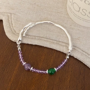 Détail macro d'un bracelet en perles avec cristaux violets et perle d'accentuation verte