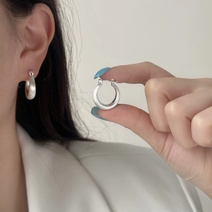 Minimalist matte silver U-shaped hoop earrings shown on ear and held for size detail