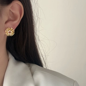 Elegant gold pearl firework earrings in a radial floral design on model