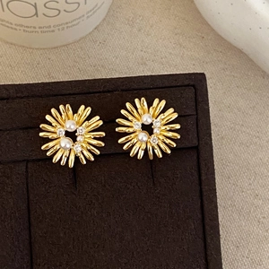 Close-up of golden sunflower earrings featuring pearls and sparkling rhinestones