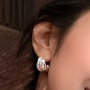 Silver multi-layer twisted rope C-shaped hoop earrings on female model's ear
