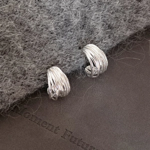 Macro detail of silver multi-layer textured C-shape earrings with intricate wired design