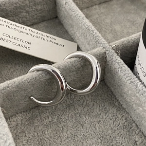 Detailed macro view of polished silver C-shaped stud earrings in a luxury jewelry box