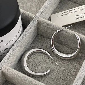 Macro detail of thick silver hoop earrings with polished mirror finish in a jewelry box