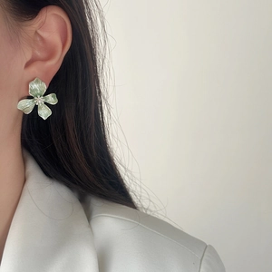 Elegant light green floral stud earrings with brushed texture on white blazer model
