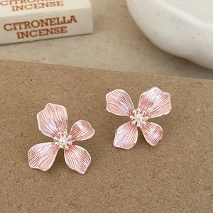 Close-up of four-petal pink enamel flower earrings with white pearl center and silver edges
