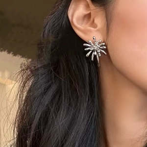 Détail macro d'une boucle d'oreille en étoile argentée au fini métal liquide