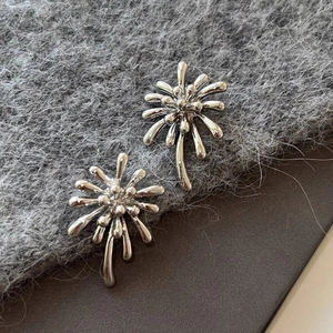 Détail macro de boucles d'oreilles feu d'artifice en argent au fini métal poli
