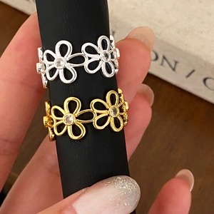 Elegant gold and silver cutout daisy rings with clear zircon stones on display
