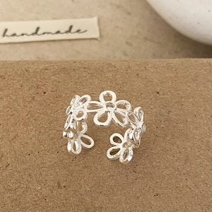 Minimalist silver open ring featuring hollow daisy flower patterns on brown paper background