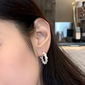 Minimalist silver hoop earrings with irregular textured finish worn on ear for sizing