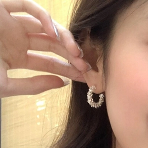 Close-up of silver-tone C-shaped hoop earrings with textured crushed metal finish