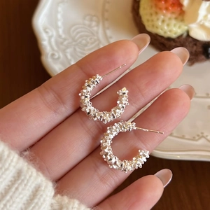 Elegant silver C-shaped hoop earrings with textured finish shown in a hand-held view