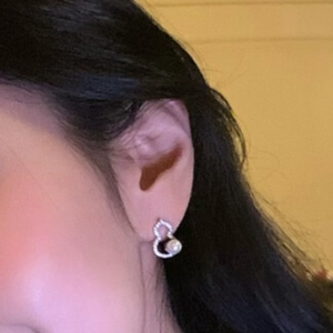 Boucles d'oreilles Wu Lou argentées élégantes avec cristaux et perle portées par un modèle