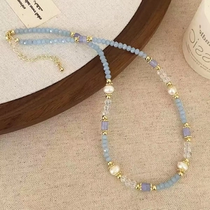 Close-up of pastel blue stone beads and pearls on a natural linen and wood setting