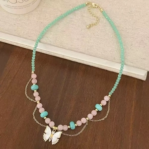 Natural stone beaded necklace with white butterfly pendant on a rustic textured background
