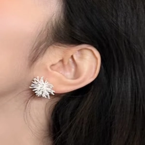 Detailed view of silver dandelion zircon stud earrings worn on a female model's ear