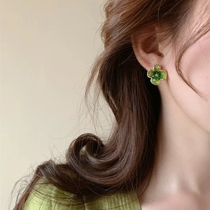 Detail of green crystal clover stud earring worn by a model with gold plating