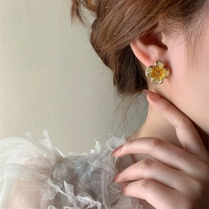Close-up of elegant yellow crystal flower stud earring on a model with white lace collar