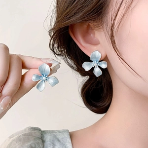 Elegant light blue flower earrings with white pearls and metal texture on a model