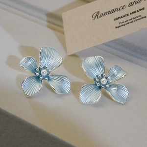 Elegant blue flower stud earrings with pearl centers and silver metal textured petals