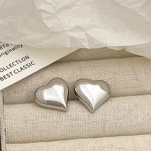 Detailed macro view of polished silver heart stud earrings inside a gift box
