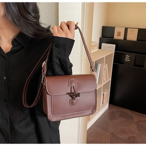 Detail of retro dark brown leather crossbody bag with white stitching and toggle closure