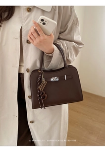Detail of dark brown leather tote with silver twist lock and minimalist creative charms