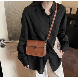 Close-up of vintage brown crossbody bag with contrast stitching and horn buckle detail