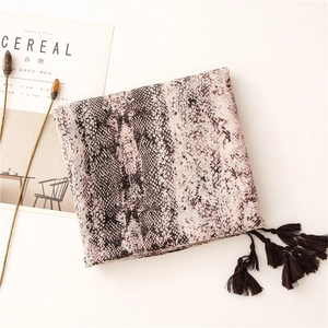 Close-up of snake print chiffon scarf featuring elegant brown tassels on a white surface