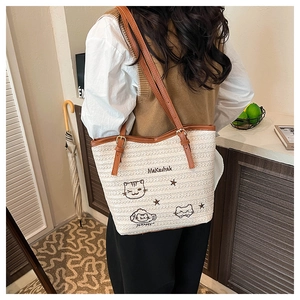 Détail du sac fourre-tout tissé crème avec broderie chat et lanières en cuir