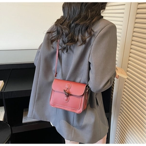 Detail of brick red leather square bag with white stitching and vintage metal lock