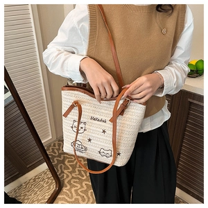 Détail du sac cabas tissé beige avec broderie chat et bandoulières en cuir chic