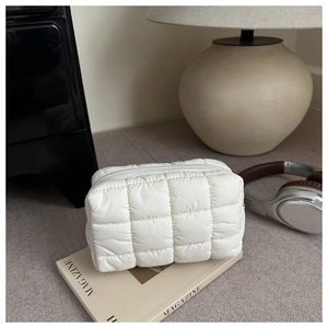Detail view of white quilted nylon toiletry bag on a book in a cozy home setting
