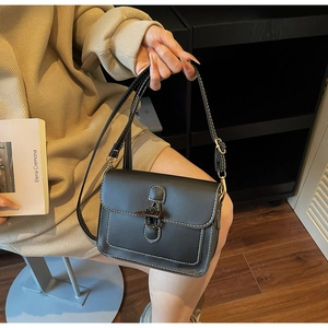 Detail of vintage black crossbody bag with white contrast stitching and bronze metal clasp