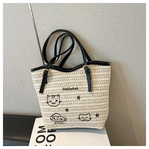 Détail du sac cabas en paille tressée avec motifs brodés de chat et d'ours cartoon