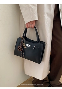 Detail of black pebble grain leather handbag featuring silver hardware and abacus charm