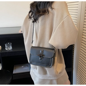 Close-up of vintage black crossbody bag with white contrast stitching and retro buckle