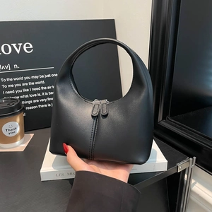 Minimalist black matte handbag with semi-circular handle and dual zipper design