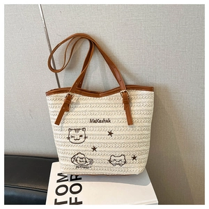 Détail de la broderie sur un grand sac cabas en paille beige avec poignées en cuir
