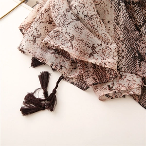 Detailed view of lightweight snake print scarf fabric with dark brown decorative tassels
