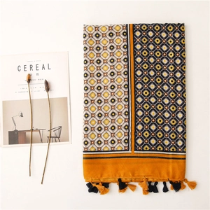 Detailed flat lay of geometric print cotton scarf with orange tassels and fringe