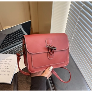 Close-up of brick red crossbody bag with contrast stitching and vintage clasp detail